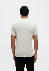 Világosszürke pamut póló rövid ujjakkal és klasszikus gallérral. Simaszövet, mintázat vagy díszítés nélkül.