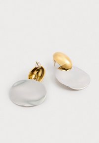 Kullatud ja hõbedased metallkõrvarõngad, mis on varustatud ülemõõdulise ovaalse kuju, poleeritud viimistluse ja post-back kinnitusega. Sile tekstuur kontrastsete värvidega.