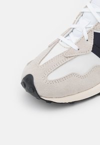 Baskets avec une tige en maille blanche, des surcouches en suède gris clair, une semelle extérieure en caoutchouc noir et des lacets blancs avec des embouts ronds.