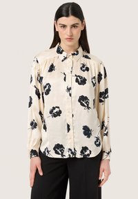 Long-sleeve button-up shirt in cream satin with black floral pattern, featuring a classic collar and elasticized cuffs.