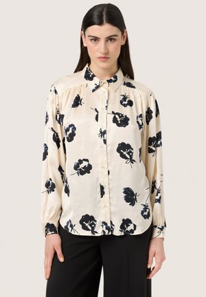 Long-sleeve button-up shirt in cream satin with black floral pattern, featuring a classic collar and elasticized cuffs.