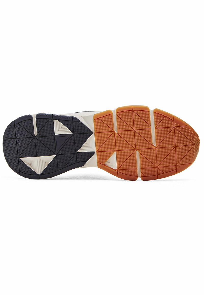 Suela de zapato con un diseño estampado que presenta secciones en negro, naranja y blanco. Texturas triangulares y rectangulares proporcionan agarre.