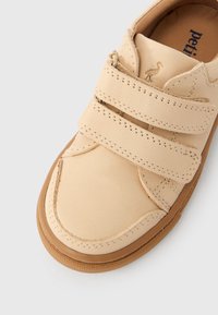 Μπεζ δερ μάτινο παιδικό παπούτσι με διπλές λουρίδες βέλκρο και καφέ λαστιχένια σόλα, με ραμμένες λεπτομέρειες και μικρό λογότυπο φλαμίνγκο.