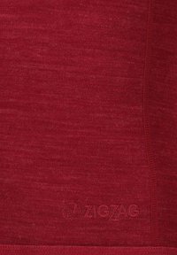 Röd texturerad tyg med en lätt melerad yta. Har en diskret präglad "ZIGZAG"-logotyp längst ner. Slät och figurnära design.