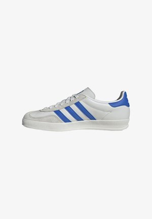 Weiße Sneaker mit blauen und grauen Akzenten, ausgestattet mit drei markanten Streifen, Schnürung vorne und einer strukturierten Sohle.