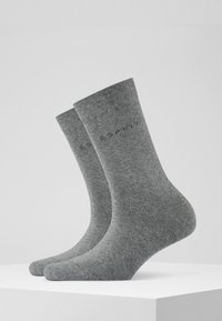 Chaussettes en coton grises à tige côtelée, avec un logo imprimé discret. Texture lisse avec un motif de couleur uniforme.