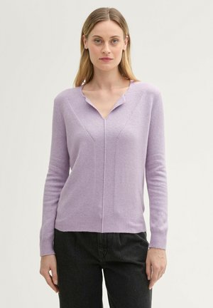 Lila Pullover mit V-Ausschnitt, langen Ärmeln und strukturiertem Vorderteil. Verfügt über vertikale Rippungen und eine taillierte Silhouette. Kombination mit schwarzen Hosen.