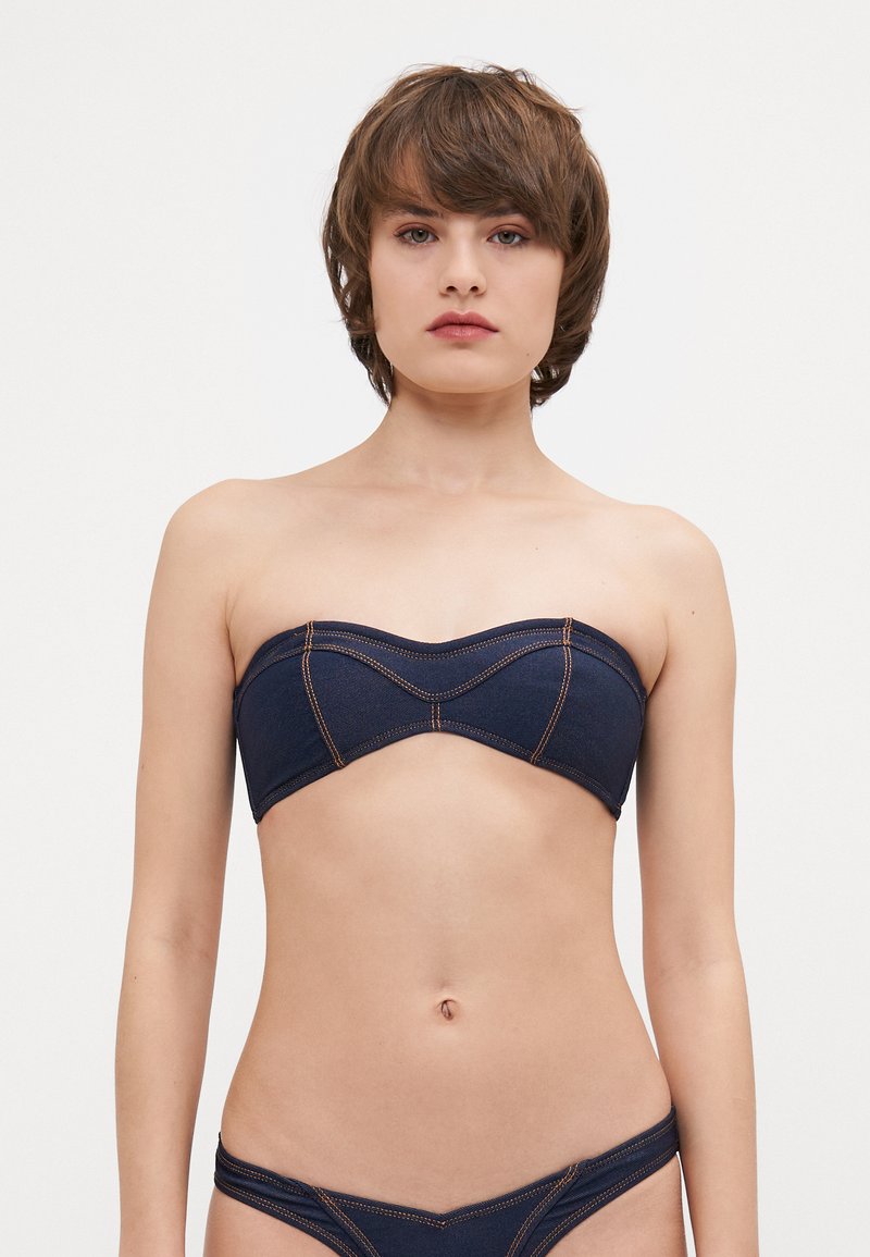 Denim bikini vrh s bandeau dizajnom, temno modre barve in kontrastnimi oranžnimi šivi. Prilegajoč in brezšiven okoli prsi.