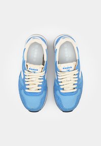 Sneaker in mesh e suede blu con lacci crema, caratterizzati da un logo e accenti bianchi, punta arrotondata e superficie testurizzata.