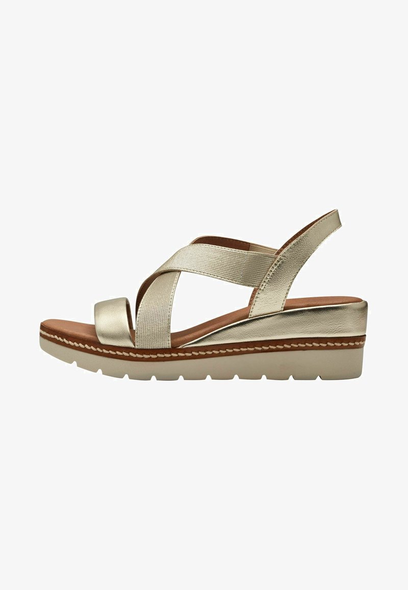 Gold metallic wedge sandals featuring crisscross straps, soft footbed, and a textured sole. The design includes a subtle stitching detail.