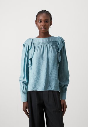 Camicia a maniche lunghe bleu chiaro con spalle arricciate e un tessuto testurizzato. Presenta dettagli arricciati attorno al colletto e ai polsini.