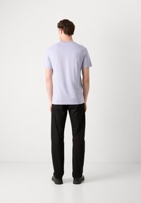 Világoslila t-shirt klasszikus kerek nyakkal, rövid ujjakkal és sima textúrával, fekete nadrággal és sötét cipővel párosítva.