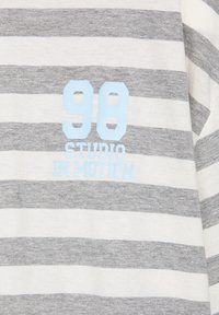 Gray and white striped fabric with light blue text reading "98 STUDIO IN MOTION" printed on it.
