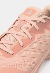 Αθλητικό παπούτσι ανοιχτού ροζ χρώματος με υλικά από δίχτυ και λάστιχο, υφή με ανάγλυφη επιφάνεια, εμφανή κορδόνια και τριών ρίγων λογότυπο.