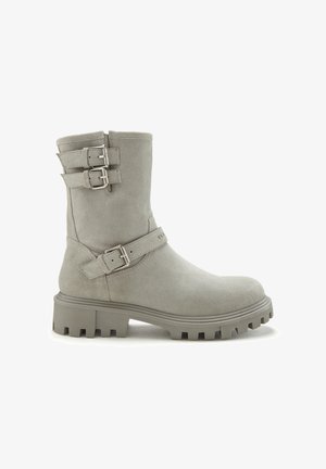 Gray suede ankle boot with two buckle accents, chunky sole, and textured finish. Minimalist design with a rounded toe and mid-calf height.