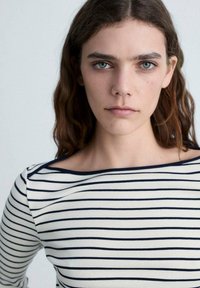 Gestreiftes Langarmoberteil in Creme und Navyblau, mit weitem Ausschnitt und schmaler Passform, aus einem weichen, elastischen Stoff.