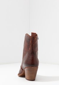 Brun faux-krokodil läder ank stövel med en texturerad yta, rund tå och staplad trähäl. Sidoglidlås för enkel påtagning.