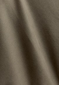 Olivroheline puuvillane kangas, millel on sile tekstuur ja kerge läige. Materjalil on peen venitus ja ühtlane kudumismuster.