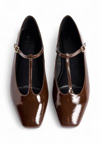 Ballerine in pelle verniciata marrone a T con punta quadrata, caratterizzate da una piccola fibbia dorata sulla cinghia alla caviglia e una finitura liscia e texture.