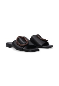 Zwarte leren instap schoenen met een vierkante neus, met een grote bruine ronde accent op de bovenkant en een platte zool.