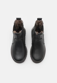 Botas de cuero negras hasta el tobillo con un suave forro interior marrón, que incluyen una tira para tirar y un diseño de punta redonda, además de una suela de goma duradera.