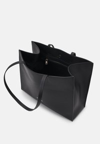 Svart lær tote bag med minimalistisk design, åpen topp og lange håndtak. Innvendig har den en glidelåslomme for organisering av gjenstander.