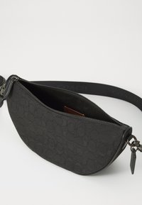 Schwarze Stoff-Umhängetasche mit geschwungener Form, geprägtem Logo-Muster und silbernem Reißverschluss. Verfügt über einen abnehmbaren Trageriemen und ein Innenfach.