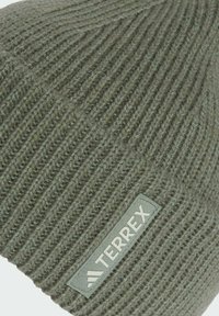 Grön stickad mössa med ribbad textur och en rektangulär tygpatch med "TERREX"-logotypen i en kontrasterande färg.