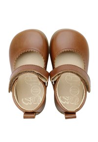 Zapatos Mary Jane de cuero marrón con bordes ondulados, correa ajustable y cierre de gancho y lazo. Interior suave y diseño resistente.