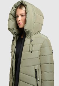 Gewatteerde winterjas in olijfgroen met een grote capuchon, zijzakken en koorddetails. Glad textuur met een gestikt patroon.