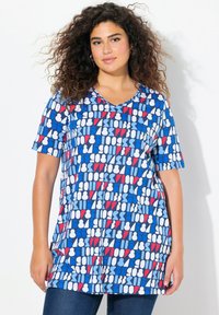Tunique à col en V à manches courtes en bleu avec des motifs géométriques en blanc et rouge. Tissu doux avec une coupe décontractée, arrivant au niveau des hanches.