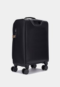 Maleta rígida negra con superficie texturizada, cuatro ruedas negras, asa superior y candado de combinación. Diseño delgado y rectangular para un transporte fácil.