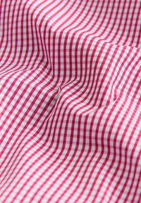 Tissu à carreaux rouge et blanc avec des plis et des rides visibles créant une surface texturée.
