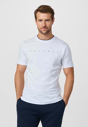 Camiseta blanca de manga corta con ribete negro y logo "HACKETT" en letras negras en el pecho; tejido liso y diseño clásico de cuello redondo.