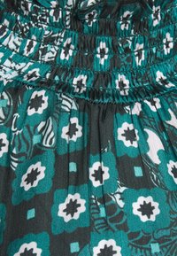 Tessuto per abito floreale teal con arricciatura, caratterizzato da un motivo di fiori bianchi e teal scuro su uno sfondo scuro. Morbido al tatto.