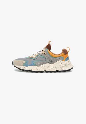 Scarpa da ginnastica multicolore con pannelli blu, grigi, beige e arancioni, lacci bianchi, suola spessa screziata e suola esterna nera texturizzata.