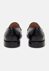 Scarpe nere in pelle con finitura liscia, punta arrotondata e tacco basso; presentano un sottile dettaglio di cucitura e un design minimalista sul tacco.