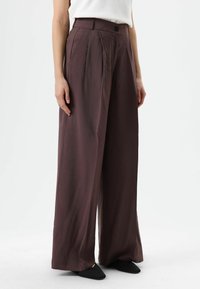 Wijdvallende broek in donkerpaarse stof, met een hoge taille, plooien aan de voorkant en een enkele knoopsluiting. Gladde textuur, minimalistisch ontwerp.