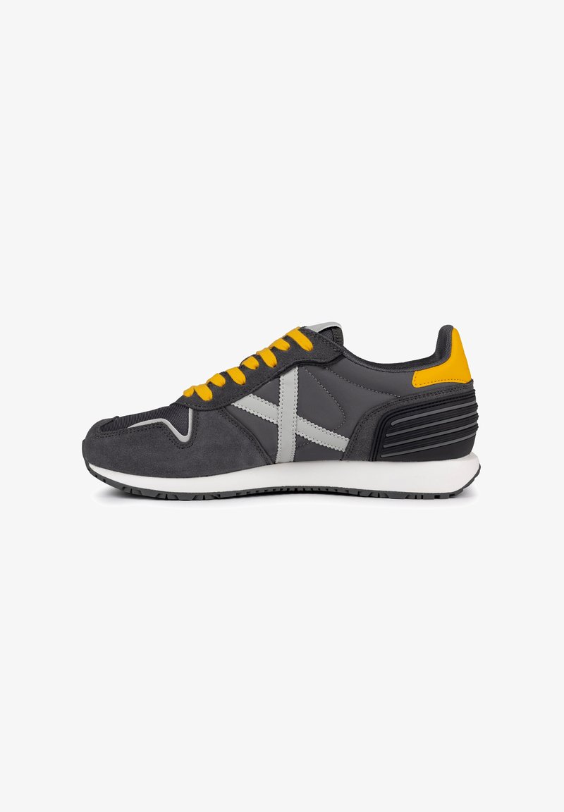 Szare buty sportowe z żółtymi sznurówkami, górna część z szarego zamszu i siateczki, biała podeszwa średnia, teksturowany czarny obcas oraz kontrastowe szare akcenty.