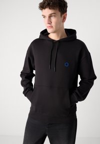 Schwarzer Kapuzenpullover mit komfortablem Schnitt, vorderer Tasche, Kordelzugkapuze und blauem, rundem Logo auf der Brust. Hergestellt aus weichem, strukturiertem Stoff.