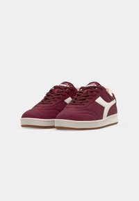Adidași din suede bordeaux cu accente albe, design cu șireturi, guler căptușit și talpă din cauciuc texturat de tip gumă. Include detalii cusute.