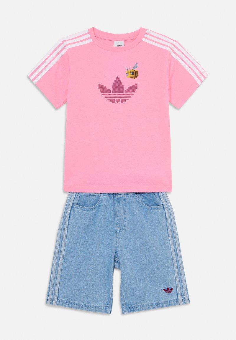 Rožinė medvilninė marškinė su pikselizuotu logotipu ir bičių grafika, derinama su šviesiai mėlynomis džinsinėmis šortais, turinčiomis šonines juostas ir logotipo siuvinėjimą.