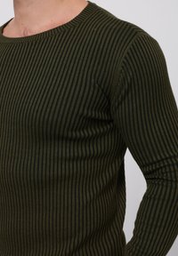 Camisa de manga larga verde oscuro con rayas verticales, escote redondeado, textura acanalada y forma ajustada, mostrando costuras uniformes en toda su superficie.