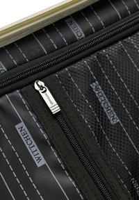 Tessuto nero testurizzato con un design a motivo, caratterizzato da una cerniera prominente e un'etichetta di marca. Accentuato con linee grigie e dettagli in rete.