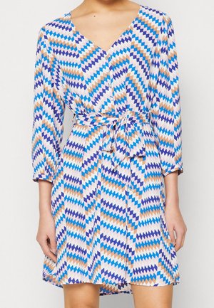 Langdurige mouw korte jurk met zigzagpatroon in blauw, paars, beige en wit, met knopen aan de voorkant en een gestrikt ceintuur in de taille.