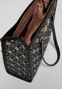 Sac fourre-tout à motifs noir et blanc avec un design structuré, doté de fermetures éclair dorées et d'une doublure intérieure rose.