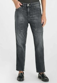 Jean en denim noir avec une coupe décontractée, dotés de poches avant angulaires, de coutures visibles et d'une coupe droite. Texture lisse et design classique.