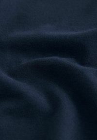 Marinebl�ått tyg med en slät yta, som har lätt veck och skrynklor, vilket föreslår ett mjukt, stretchigt trikåmaterial.