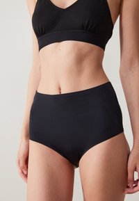 Svart BH og høytlivs undertøysett. Glatt stoff, elastisk materiale, enkel design og sømløse kanter. Ingen synlige mønstre eller aksenter.
