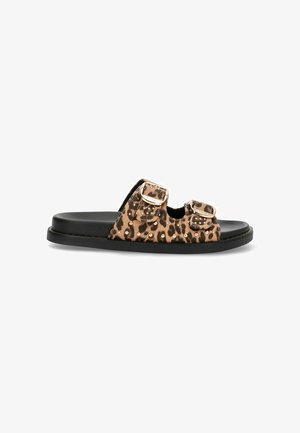 Chancla deslizante con estampado de leopardo, que presenta dos hebillas ajustables, una suela plana negra y tejido texturizado con acentos de tachuelas metálicas.